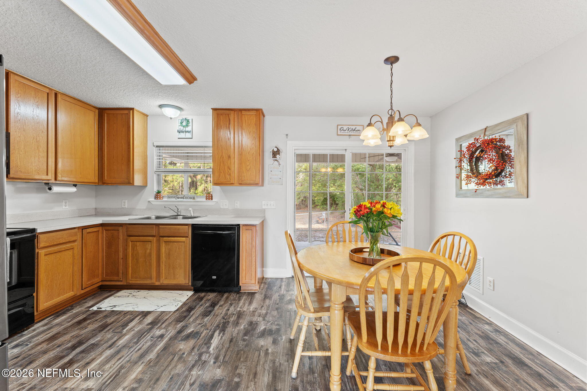 482 North 3rd Street Macclenny, FL 32063 - Photo 8 of 32 a kitchen with stainless steel appliances granite countertop a stove top oven a sink dishwasher a dining table and chairs with wooden floor