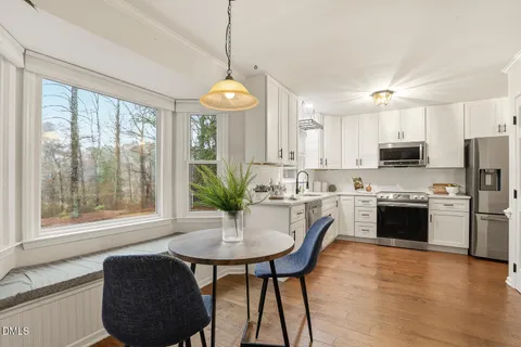 a dining room with wooden floor a chandelier a wooden table and chairs