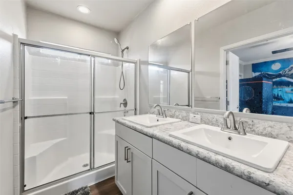 a bathroom with a double vanity sink mirror and shower