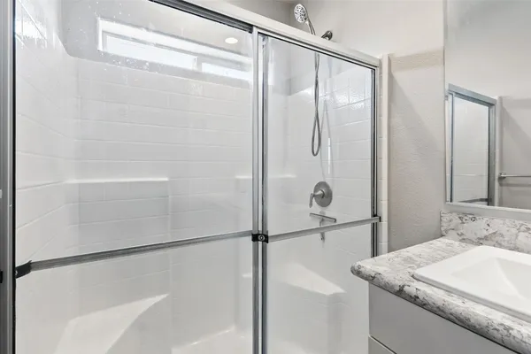 a bathroom with a granite countertop shower sink and mirror