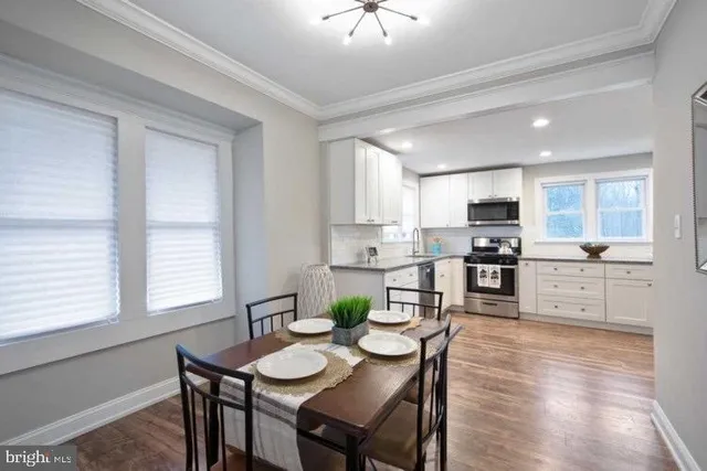 a kitchen with stainless steel appliances kitchen island granite countertop a dining table chairs and a refrigerator