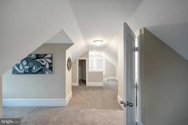 a view of a hallway with wooden floor and a bathroom