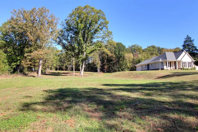 a view of a house with a big yard and large trees