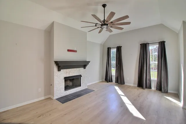 a view of an empty room with window and wooden floor