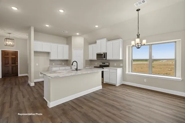 a kitchen with kitchen island granite countertop a stove a sink a center island and a wooden floor