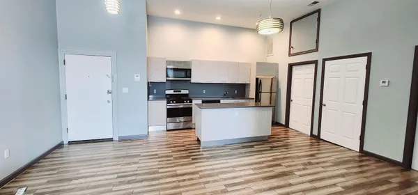 a kitchen with stainless steel appliances granite countertop a refrigerator a stove top oven a sink and dishwasher with wooden floor
