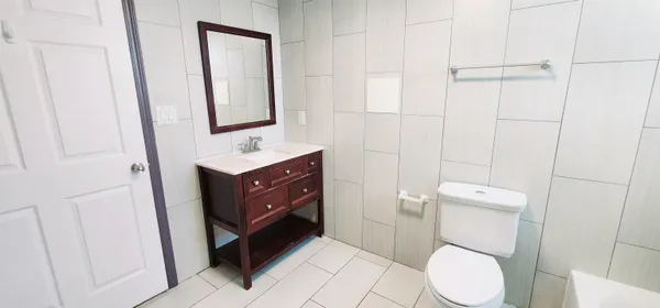 a bathroom with a toilet sink vanity and mirror