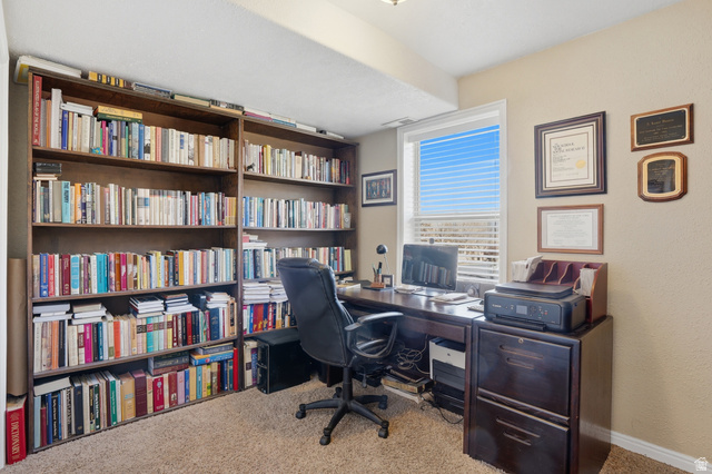 7737 Ranches Parkway Eagle Mountain, UT 84005 - Photo 19 of 28 Dedicated office space featuring extensive built-in shelving, a large window with white blinds, and neutral-toned wall paint
