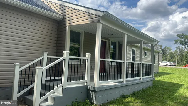 a view of small house with backyard and porch
