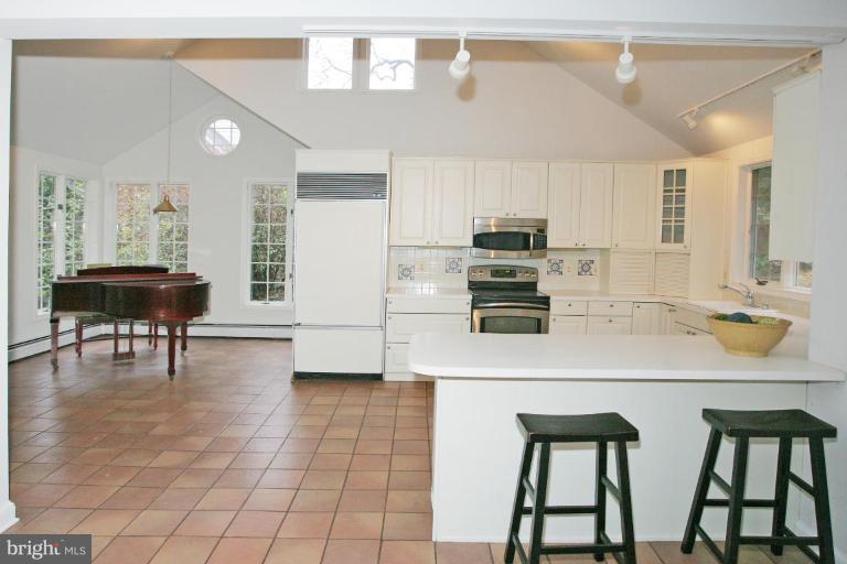 8703 Ridge Road Bethesda, MD 20817 - Photo 6 of 8 a kitchen with stainless steel appliances a dining table chairs and a refrigerator