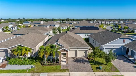 an aerial view of a house with a yard lake and trees all around