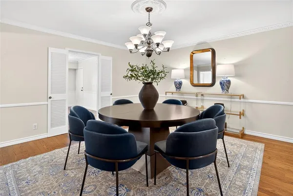 a dining room with chandelier and wooden floor
