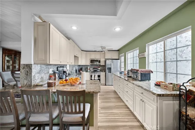 a kitchen with stainless steel appliances granite countertop a stove top oven a sink a dining table and chairs