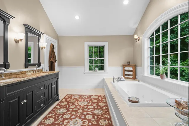 a spacious bathroom with a tub double sink window and mirror