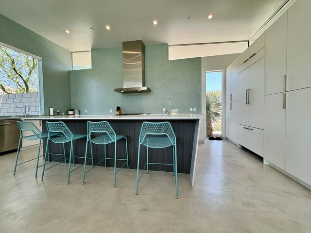 a kitchen with kitchen island stainless steel appliances a sink and chairs