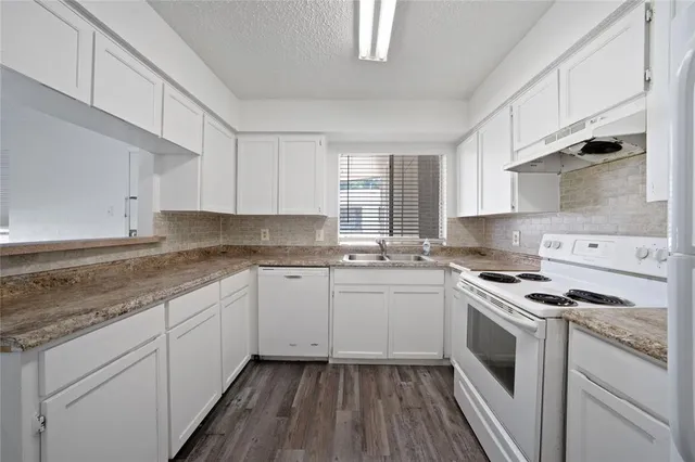 a kitchen with granite countertop white cabinets sink and appliances