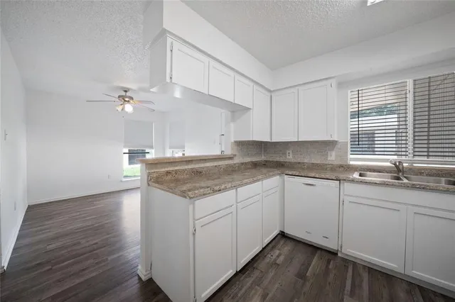 a kitchen with granite countertop white cabinets and a sink