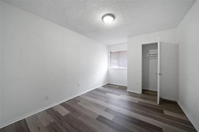 a view of an empty room with closet and a window