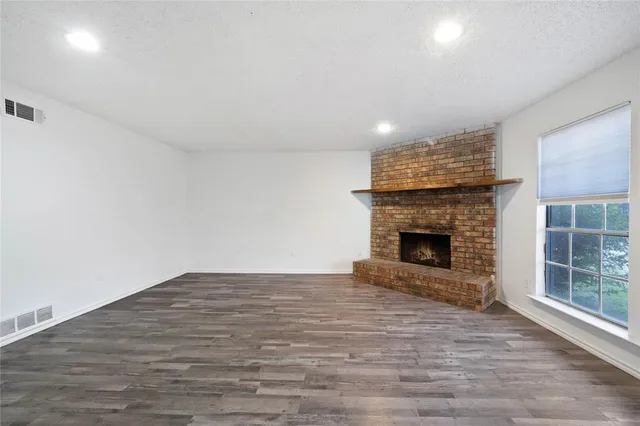 a view of empty room with wooden floor and fireplace