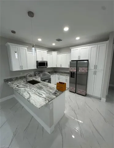 a kitchen with stainless steel appliances granite countertop a refrigerator oven a sink a stove and white cabinets