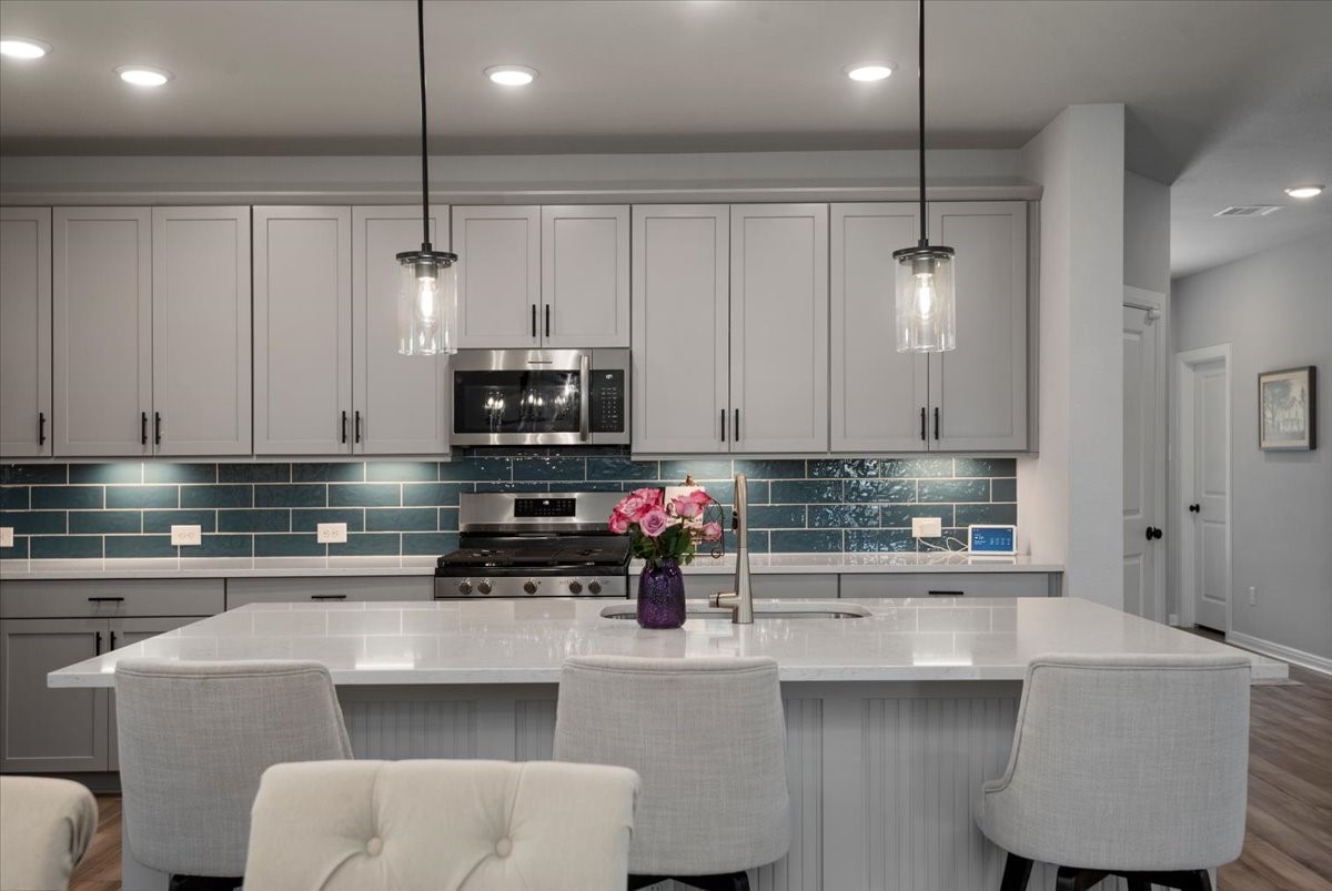 27134 Cutleaf Daisy Court Hockley, TX 77447 - Photo 11 of 46 The kitchen is stunning with the blue tile backsplash, under cabinet lighting, pendant lighting, and stainless appliances.