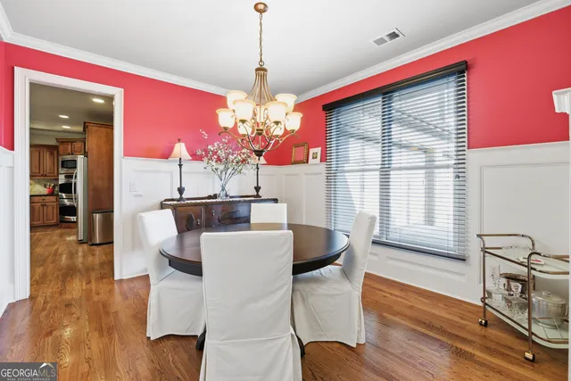 a dining room with wooden floor a chandelier a wooden table and chairs