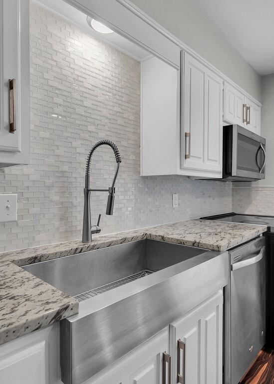 1362 South 12th Street, Unit 22 Waco, TX 76706 - Photo 12 of 31 Stainless steel farmhouse sink with a gooseneck faucet, light-toned granite countertops, white shaker-style cabinetry, and a subway tile backsplash