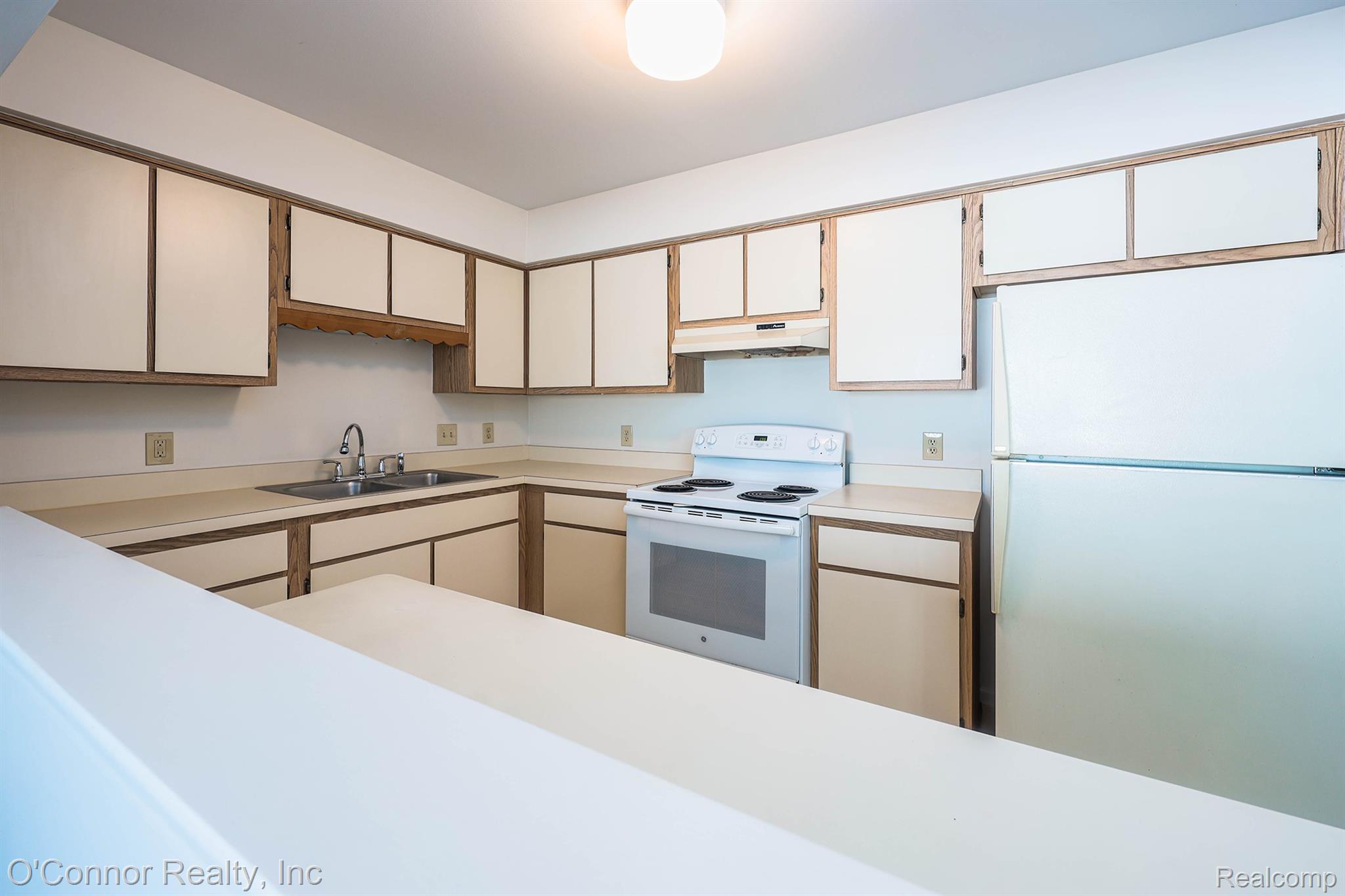 1660 River Road, Unit 53 Marysville, MI 48040 - Photo 14 of 31 Two tone kitchen with white appliances, light countertops, and two tone cabinetry