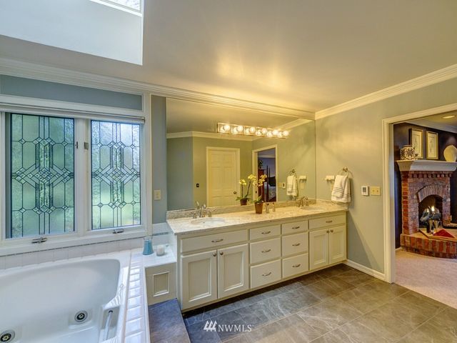 a spacious bathroom with a double vanity sink a large mirror and a bathtub next to a window