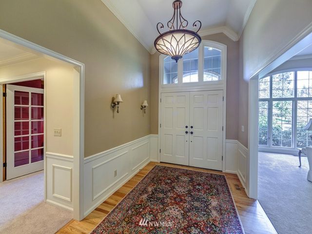 a view of a hallway with wooden floor and chandelier