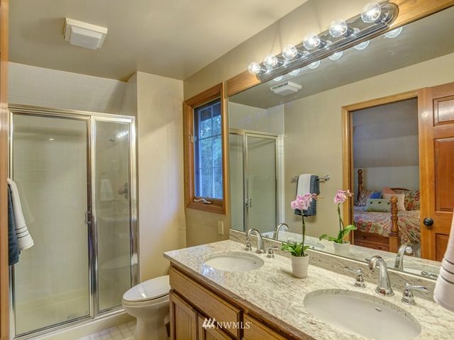a bathroom with a granite countertop double vanity sink toilet and shower