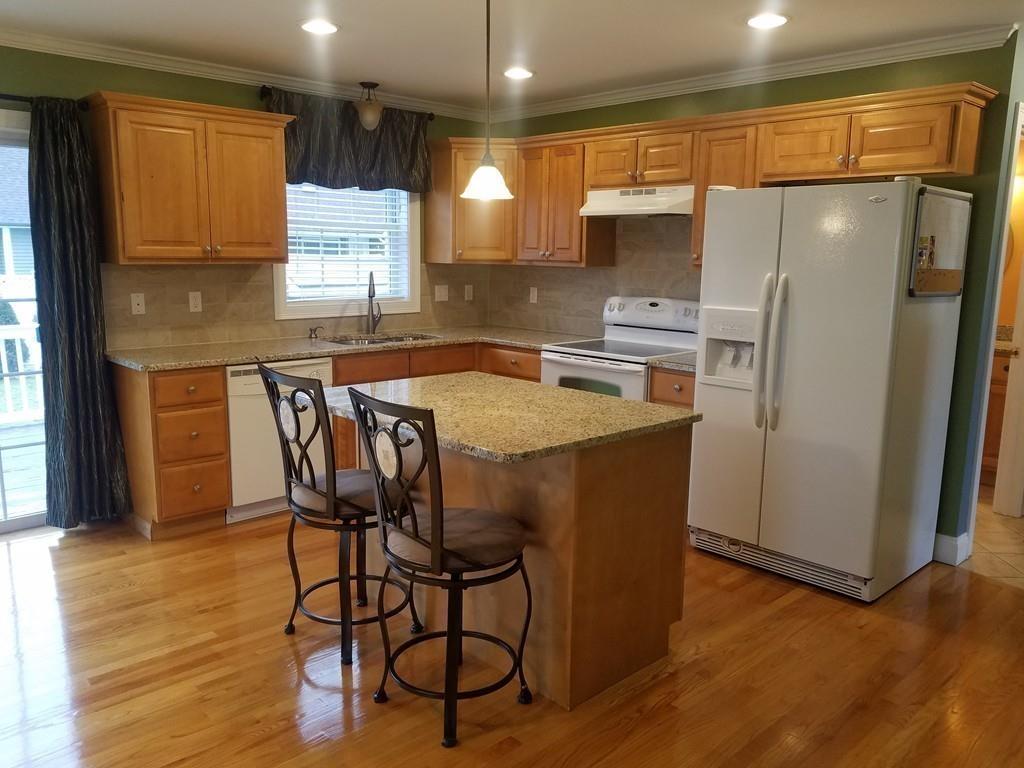 18 Channing Road East Longmeadow, MA 01108 - Photo 12 of 40 a kitchen with stainless steel appliances a refrigerator a stove a sink a dining table and chairs with wooden floor