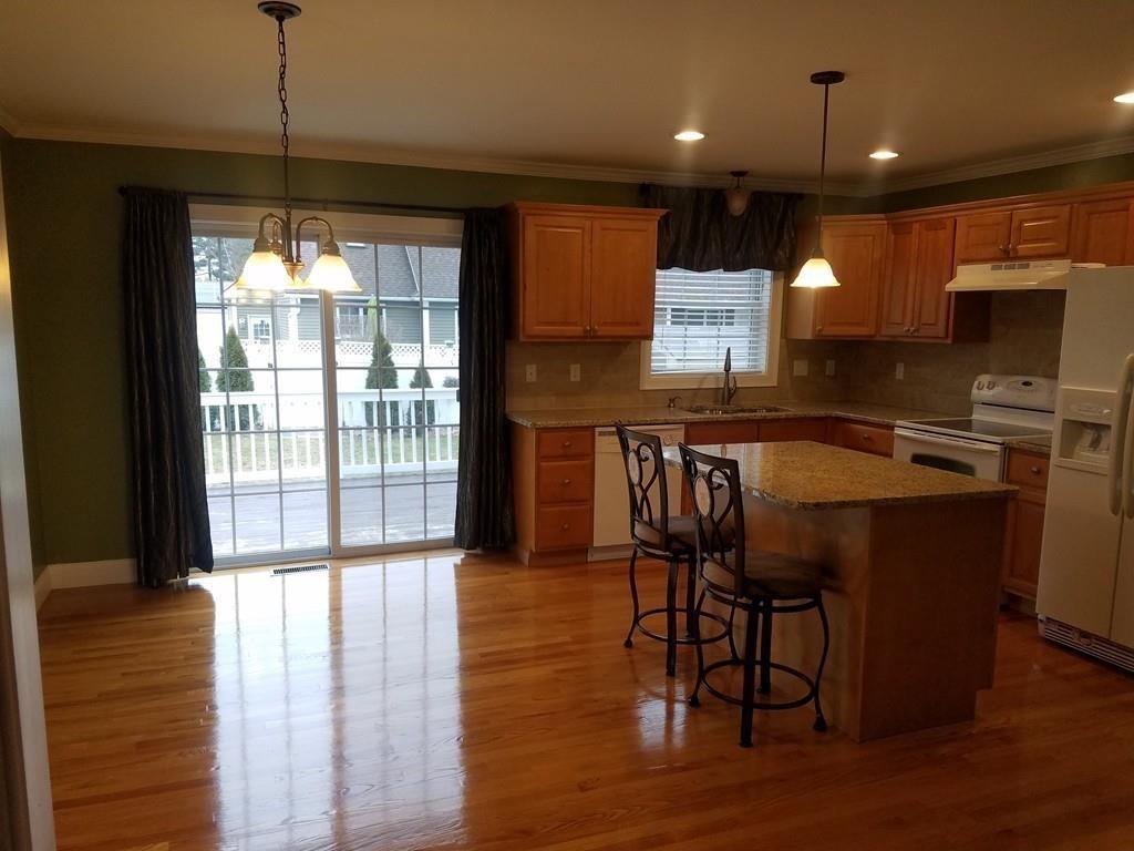 18 Channing Road East Longmeadow, MA 01108 - Photo 13 of 40 a kitchen with stainless steel appliances granite countertop a stove top oven a refrigerator and a dining table with wooden floor