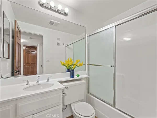 a bathroom with a granite countertop toilet sink and mirror