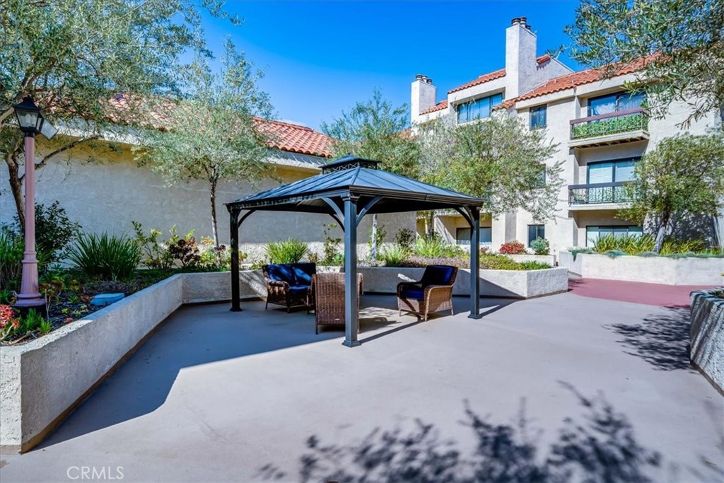 8180 Manitoba Street, Unit 302 Playa del Rey, CA 90293 - Photo 22 of 31 a view of a patio with a table and chairs under an umbrella with potted plants