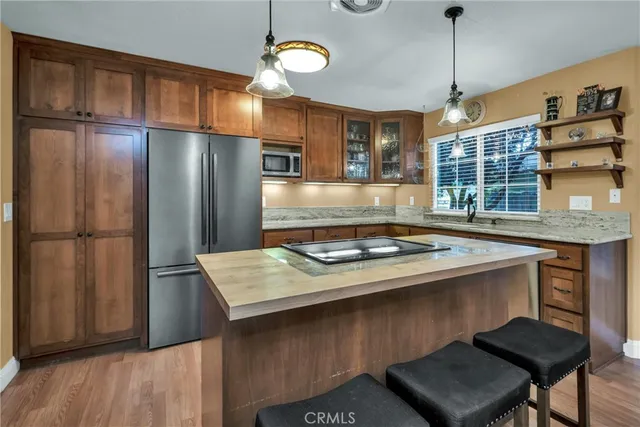 a kitchen with stainless steel appliances granite countertop a refrigerator a stove and a sink with wooden floor