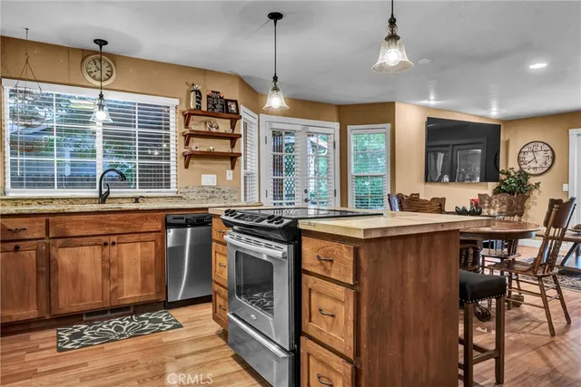 a kitchen with stainless steel appliances granite countertop a stove a sink dishwasher and a refrigerator with wooden floor