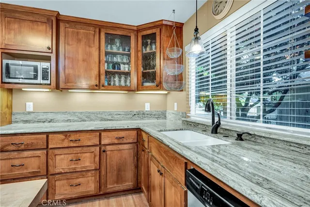 a kitchen with granite countertop wooden cabinets a sink and dishwasher