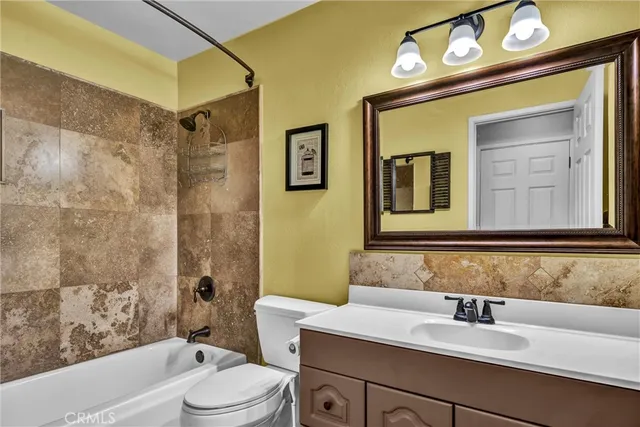 a bathroom with a sink vanity mirror toilet and bathtub
