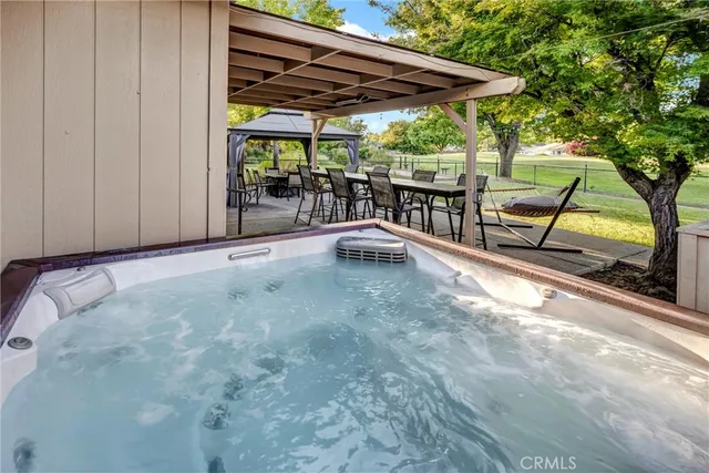 a view of a patio with table and chairs under an umbrella with a large tree