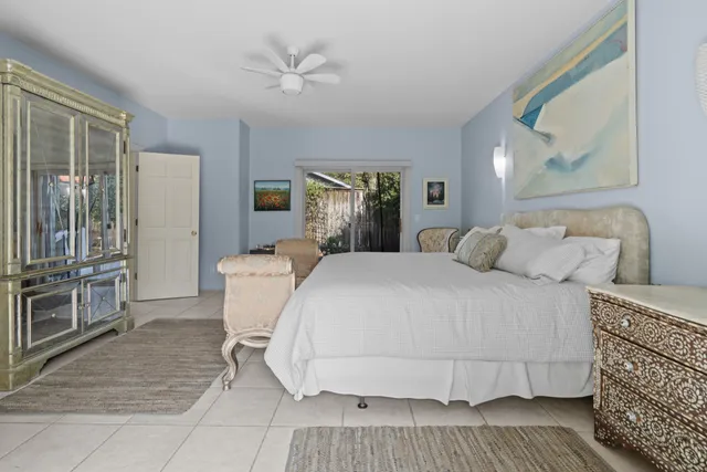 a bedroom with a large bed a chandelier with dresser and mirror