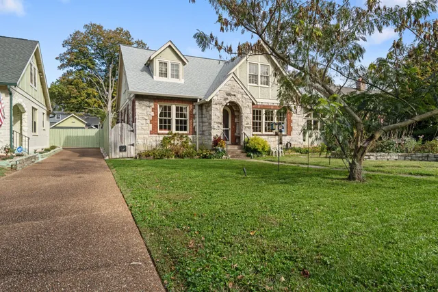 a front view of a house with garden and trees