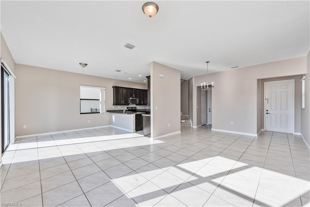 8732 Madrid Circle Naples, FL 34104 - Photo 4 of 15 Unfurnished living room featuring plenty of natural light, light tile patterned floors, and a notable chandelier