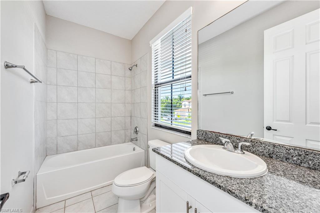 8732 Madrid Circle Naples, FL 34104 - Photo 10 of 15 Full bathroom with tiled shower / bath combo, tile patterned flooring, vanity, and toilet