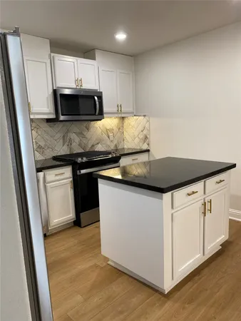 a kitchen with granite countertop white cabinets and a stainless steel appliances