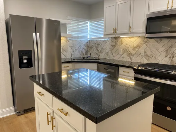 a kitchen with stainless steel appliances granite countertop a sink a stove and a refrigerator