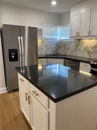 a kitchen with stainless steel appliances granite countertop a sink and a refrigerator