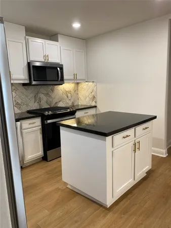 a kitchen with granite countertop white cabinets and stainless steel appliances