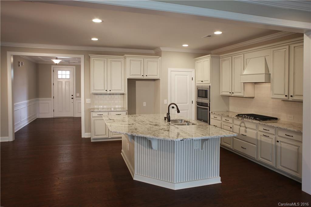 1033 Emory Lane, Unit 70 Fort Mill, SC 29708 - Photo 4 of 21 a kitchen with kitchen island granite countertop a stove a sink a refrigerator and white cabinets with wooden floor