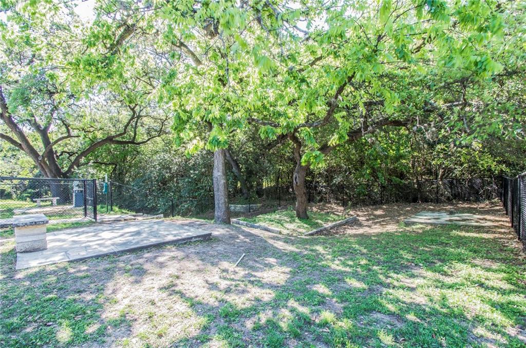3204 Manchaca Road, Unit 302 Austin, TX 78704 - Photo 17 of 20 Mature trees shade a fenced community dog park area with a convenient waste station.